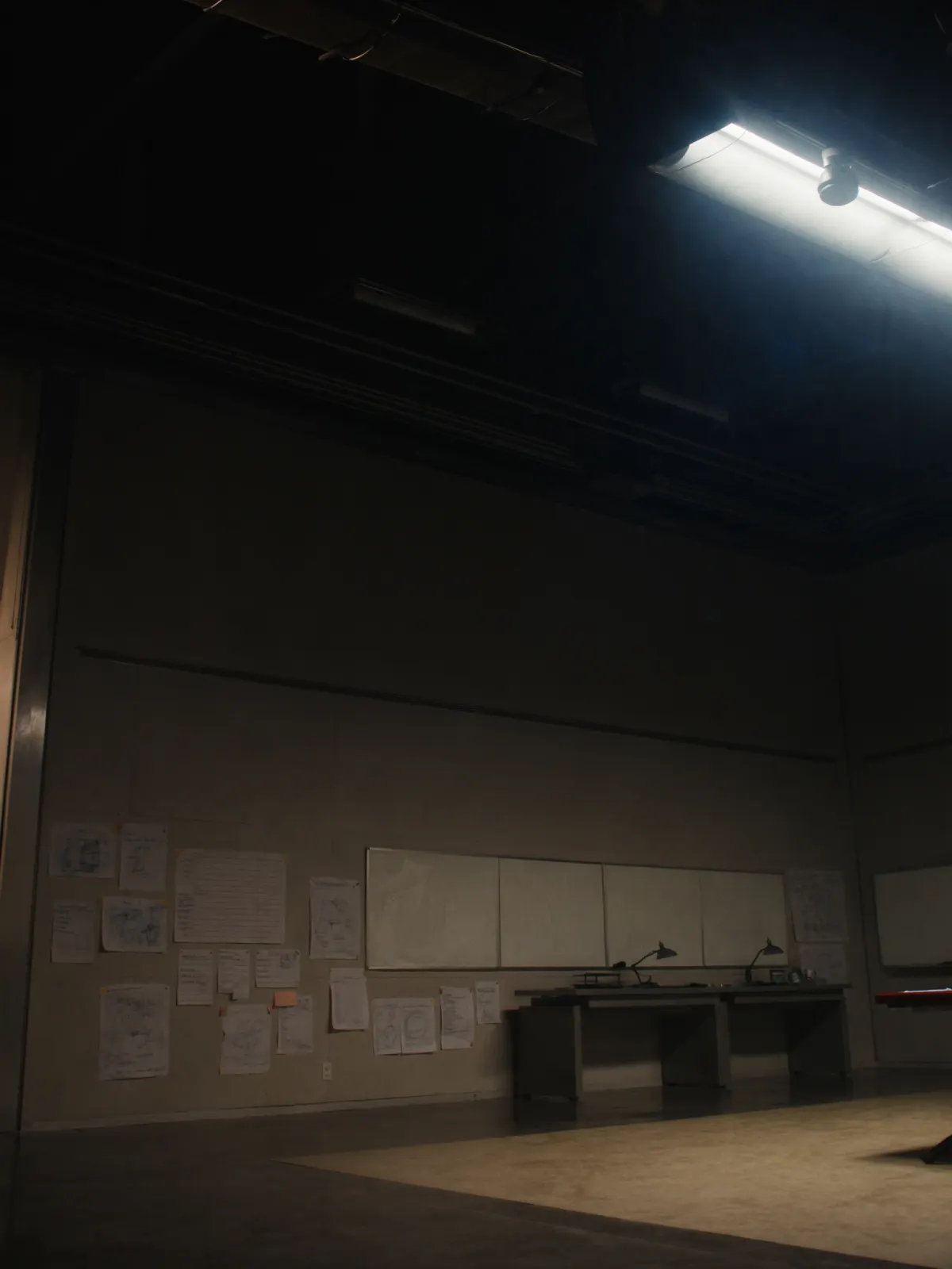 Engineering War Room — anonyme Engineering-Skizzen an der Wand, einzelner Lichtkegel von oben, als Sinnbild der dokumentierten Pilot-Arbeit